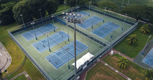 Blue tennis hard courts with checked floodlights.